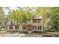 Charming two-story brick home with a well-manicured lawn and mature tree in a serene, wooded setting at 185 Chimney Springs, Tyrone, GA 30290