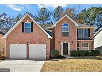 View of two-story brick home featuring an attached two-car garage and well-maintained landscaping at 6322 Shell Sw Dr, Atlanta, GA 30331