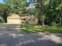Charming single-Gathering home with attached garage and inviting curb appeal surrounded by lush greenery and mature trees at 3244 Harbor Woods Rd, Decatur, GA 30034