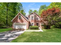 Charming brick home with a manicured lawn, mature trees, and an attached two car garage at 205 Huntwood Ct, Ellenwood, GA 30294