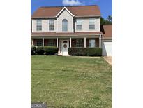 Charming two-story home featuring a welcoming front porch and well-maintained landscaping at 5458 Stagecoach Rd, Ellenwood, GA 30294