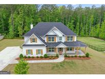 Stunning two-story white home featuring a large covered porch and beautiful, mature landscaping at 152 Creekrise Pl, Palmetto, GA 30268