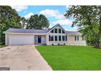 Charming single-story home with a well-maintained lawn, a two-car garage and a beautiful window design at 4397 Bluebird Ln, Lithia Springs, GA 30122