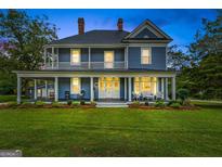Charming two-story blue home featuring a large wrap-around porch and well-manicured lawn at 29 Indian Creek Rd, Locust Grove, GA 30248