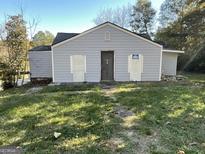 Exterior view of the light blue house with boarded-up windows, showing the front and side at 305 Fairburn Nw Rd, Atlanta, GA 30331