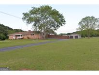Charming ranch-style home featuring a well-maintained lawn, brick exterior, and a long driveway leading to a detached garage at 2647 Mount Carmel Rd, Hampton, GA 30228