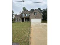 Charming two-story brick home with a well-manicured lawn and attached two-car garage at 606 Gardner Rd, Stockbridge, GA 30281