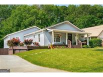 Charming single-story home with a welcoming front porch, lush landscaping, and a well-manicured lawn at 1928 Main Nw St, Atlanta, GA 30318