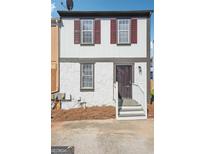 Charming home featuring a distinctive stone facade, red shutters, and a welcoming gated entryway with wooden stairs at 2047 Charter Ln, Lithonia, GA 30058