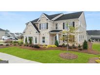 New two-story home featuring a brick facade, green lawn, and a well-manicured landscape at 1813 Quaker St, Hampton, GA 30228