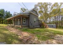 Charming gray home featuring a metal roof, inviting front porch and walkway, and freshly landscaped yard at 59 S Old Hwy 27, Roopville, GA 30170