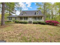 Charming one-story home featuring a quaint porch, green shutters, and well-maintained landscaping at 130 Ashley Trace Dr, Locust Grove, GA 30248