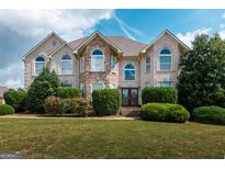 Elegant two-story home with a brick and stone facade, arched windows, and manicured landscaping at 313 Masters Club Blvd, Hampton, GA 30228