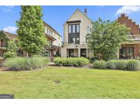 Landscaped backyard featuring manicured lawn, shrubs, trees and a modern home with a brick facade and black framed windows at 145 Kelmscott Ln, Fayetteville, GA 30214