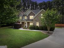 Charming two-story brick home with manicured lawn, mature trees, and inviting driveway at 204 Carmell Ct, Mcdonough, GA 30252