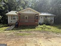 Charming one-story home with a covered porch and mature trees surrounding the property at 5552 Smithfield Rd, Bowdon, GA 30108