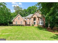 Beautiful brick two-story home with a well-manicured lawn and mature trees at 255 Emerald Lake Dr, Fayetteville, GA 30215