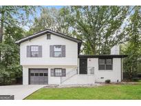 Charming two-story home with a well-manicured lawn, painted white brick and siding, and a grey garage door at 1590 Sw Cherry Hill Ln, Conyers, GA 30094