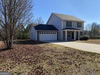 Charming two-story home with a two car garage and a long driveway, surrounded by a yard full of fall foliage at 253 Whistle Way, Locust Grove, GA 30248