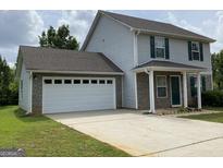Charming two-story home featuring a gray siding, a two-car garage, and a well-maintained front yard at 253 Whistle Way, Locust Grove, GA 30248