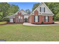Charming brick home with manicured lawn and mature trees offers classic curb appeal at 215 Murphy Creek Ln, Fayetteville, GA 30215