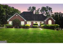 Charming red brick home featuring a well-manicured lawn and mature landscaping at 70 Lake Charles Xing, Covington, GA 30016