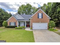 Inviting brick home with a well-manicured lawn, charming front porch, and a two-car garage at 4985 Rolling Rock Dr., Sugar Hill, GA 30518
