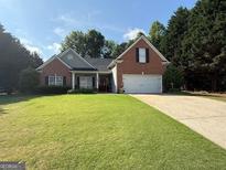 Charming one-story brick home with manicured lawn, attached garage, and well-maintained landscaping at 4985 Rolling Rock Dr., Sugar Hill, GA 30518