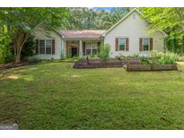 Inviting single-story home with a well-manicured lawn and charming exterior details, including shutters and a garden at 205 N Strathmore Dr, Sharpsburg, GA 30277