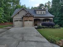 Charming home featuring a two-car garage, stone accents, covered porch and established landscaping at 57 Deer Creek Run, Moreland, GA 30259