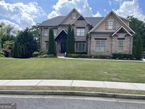 Stunning two-story brick home with manicured lawn, mature trees, and meticulous landscaping at 2220 Cambridge Hill Ct, Dacula, GA 30019