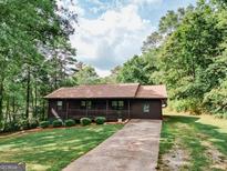 Charming single-story home with a welcoming front porch, long driveway, and lush green lawn at 134 Ashwood Dr, Waco, GA 30182