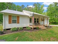 Charming white home with a cozy front porch, rocking chairs, and beautiful landscaping at 180 E Ranchette Rd, Temple, GA 30179