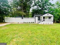 Charming one-story home boasts a lush lawn and white picket fence, blending comfort and classic style at 2502 Barge Sw Rd, Atlanta, GA 30331