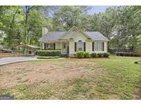 Charming single-story home with manicured lawn, covered parking, and lush landscaping at 40 Green Leaf Cir, Hampton, GA 30228