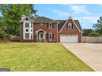Charming two-story brick home with a well-manicured lawn and a delightful light blue front door at 317 Calgary Dr, Peachtree City, GA 30269