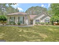 Charming single story home featuring a manicured lawn, cozy exterior, and beautiful landscaping at 15 Riverside Pkwy, Sharpsburg, GA 30277