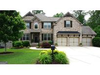 Charming brick home featuring a three-car garage and a beautifully landscaped front yard at 5760 Winding Lakes Dr, Cumming, GA 30028