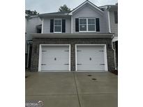 Two-car garage with brick veneer and white doors beneath gray siding and black shutters at 1155 Park Center Nw Cir, Austell, GA 30168