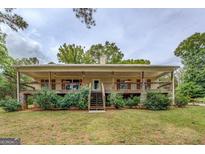 Charming ranch home featuring a wraparound porch, stone accents, and landscaped front yard at 4979 Snook Thompson Se Rd, Oxford, GA 30054