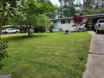 Charming front yard featuring a well-maintained lawn and a white painted brick home with blue door and mature landscaping at 3969 W Hilda Cir, Decatur, GA 30035
