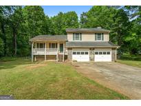 Two-story home with a two-car garage and a charming front porch nestled among mature trees at 632 Cloudland Dr, Stockbridge, GA 30281