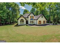 Charming two-story home with a manicured lawn, striking black trim, and rustic wooden shutters at 857 Cooper Rd, Social Circle, GA 30025