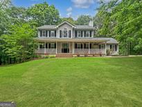 Charming two-story home with a welcoming porch, lush lawn, and surrounded by mature trees at 715 Frog Rd, Locust Grove, GA 30248