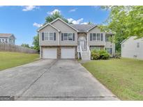 Charming two-story home featuring a two-car garage, landscaped yard, and inviting front entrance at 1341 Huey Rd, Douglasville, GA 30134