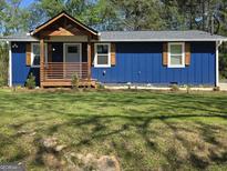 Charming home boasts a blue exterior with a cozy front porch, inviting curb appeal and mature trees at 95 Mccoy Dr, Carrollton, GA 30116
