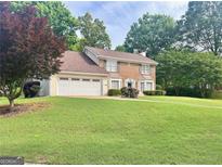 Charming two-story brick home with a manicured lawn and an attached two-car garage at 130 Floss Flower Ct, Roswell, GA 30076