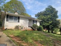 Charming single-story home featuring a brick facade, mature trees, and a cozy entrance, perfect for comfortable living at 7588 Covington Hwy, Lithonia, GA 30058