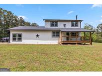 This country farmhouse features a covered wooden porch and a spacious yard at 2955 Peeksville Rd, Locust Grove, GA 30248