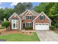 Charming two-story brick home with well-manicured lawn and a two-car garage in a lush, green neighborhood at 7020 Grand View Way, Suwanee, GA 30024